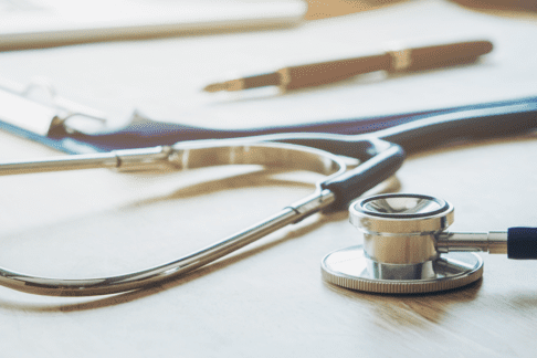 header-2 Stethoscope with clipboard and pen on desk