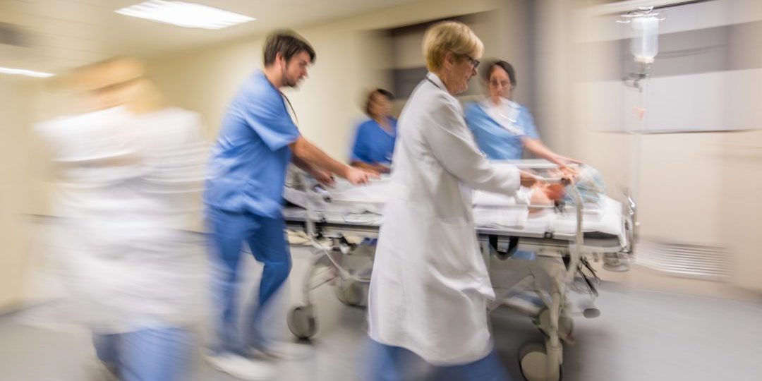 Doctors and nurse wheeling patient on stretcher in hospital's corridor.