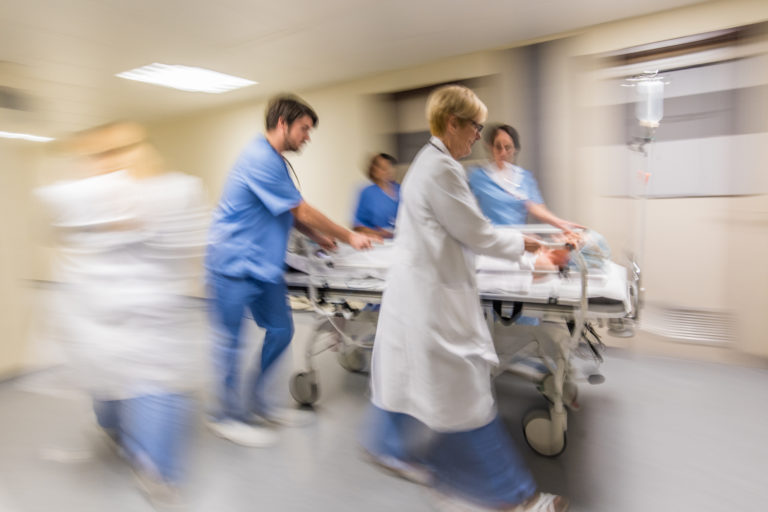 Doctors and nurse wheeling patient on stretcher in hospital's corridor.