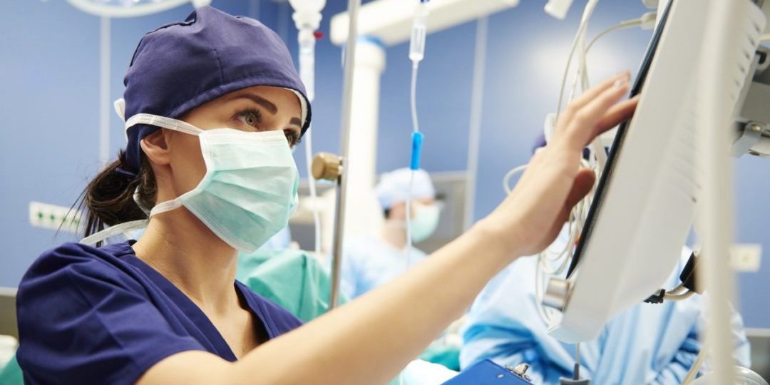 female healthcare worker with mask enters information on monitor