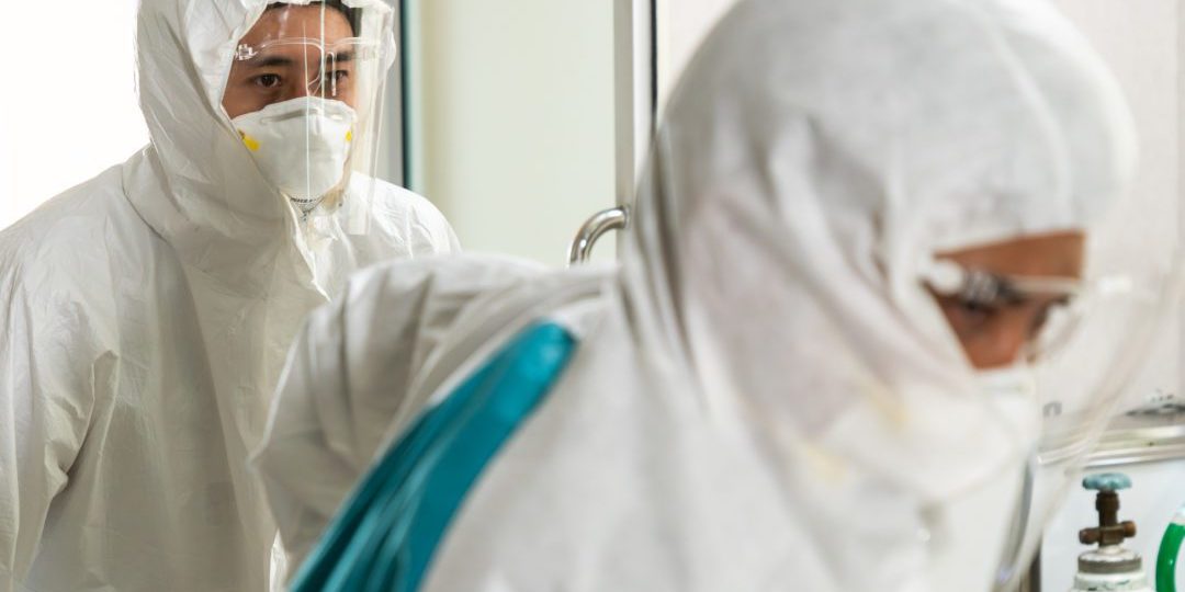 Emergency medic and doctor moving patient to emergency room in hospital . Doctor wears protective suit and face mask in concept of coronavirus and covid 19 protection and quarantine .