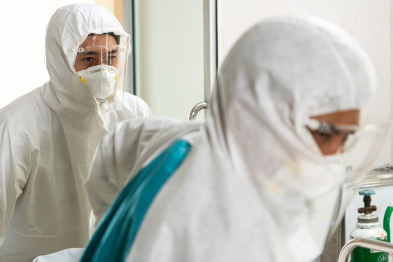 Emergency medic and doctor moving patient to emergency room in hospital . Doctor wears protective suit and face mask in concept of coronavirus and covid 19 protection and quarantine .