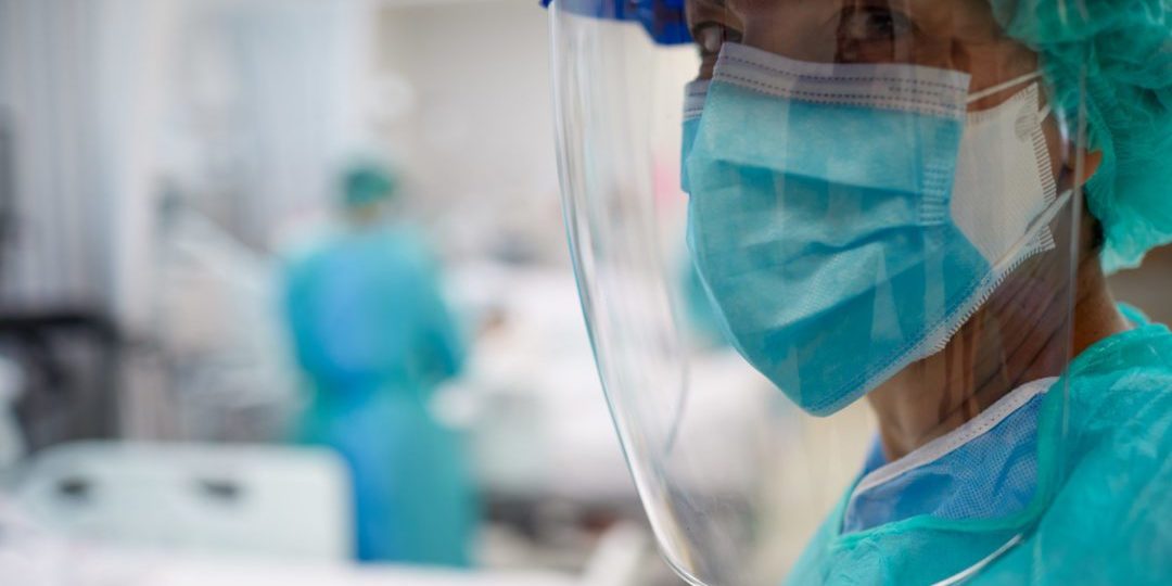 Close up view of a doctor wearing surgical mask and a face shield.