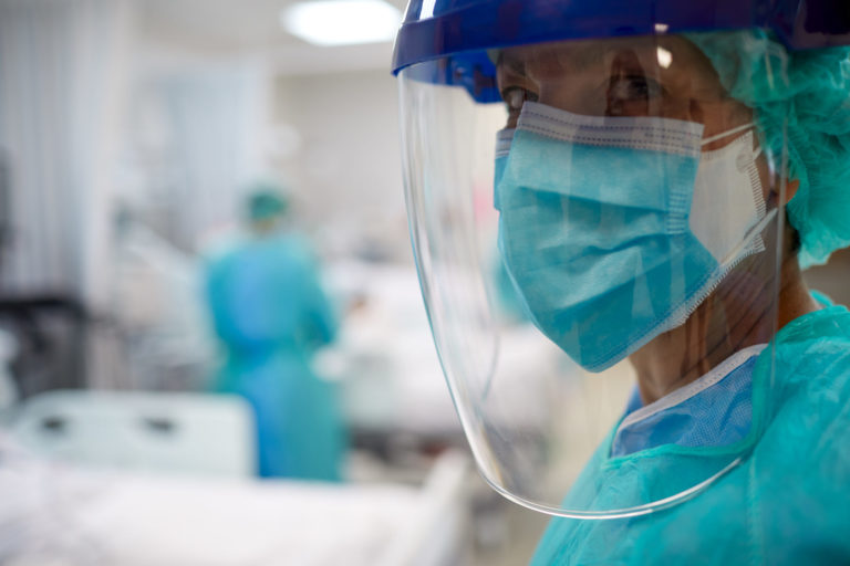 Close up view of a doctor wearing surgical mask and a face shield.