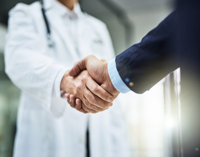 Cropped shot of a doctor shaking hands with a businessman