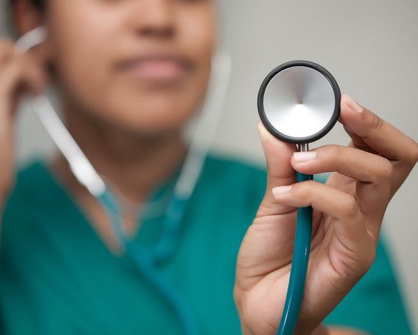A female healthcare professional taking a reading using a stethoscope and carefully listening to form a diagnosis.