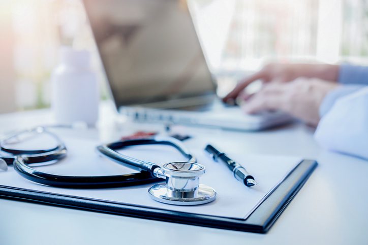 Stethoscope with clipboard and Laptop on desk Doctor working in hospital writing a prescription Healthcare and medical concept test results in background vintage color selective focus.