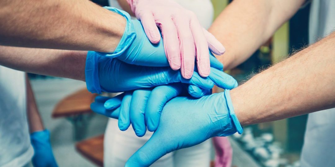 Gloved hands of group of healthcare workers