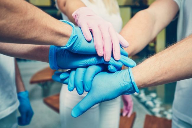 Gloved hands of group of healthcare workers