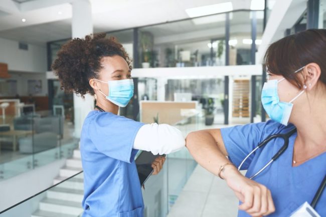 black nurse and white nurse bumping elbows