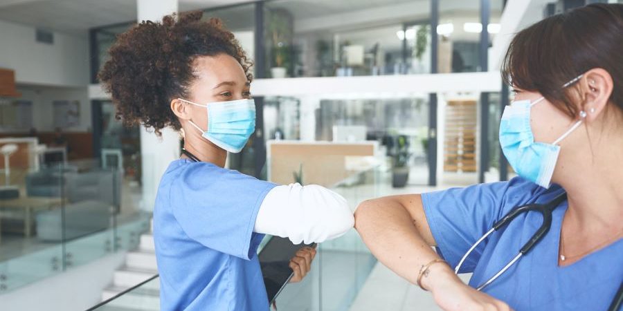 black nurse and white nurse bumping elbows