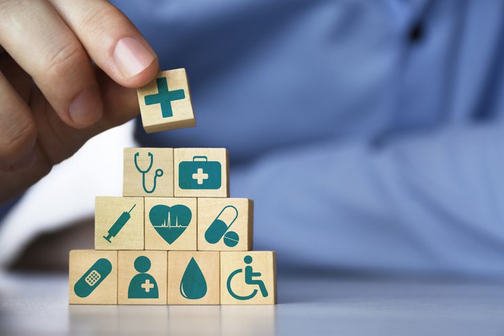 Medical health insurance concept. Men's hand arranging wood blocks with healthcare medicine icons