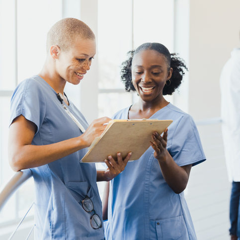 A mid adult female nurse works with a young adult female nursing student.
