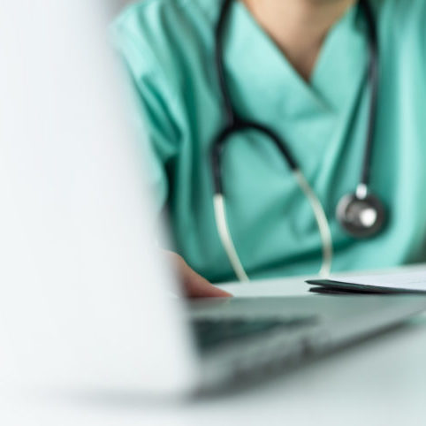 Asian female Nurse or Surgeon Doctor in green uniform working on laptop and writing something information of patient in paperwork checklist.