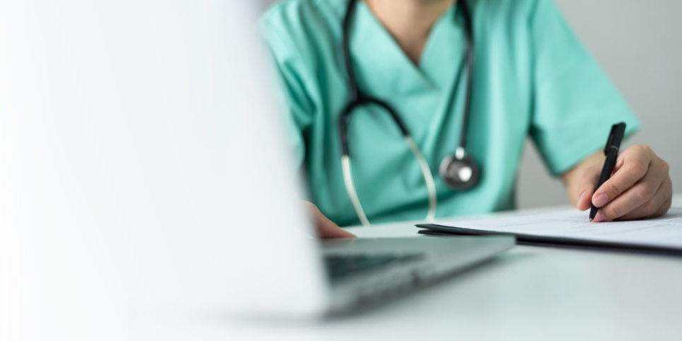 Asian female Nurse or Surgeon Doctor in green uniform working on laptop and writing something information of patient in paperwork checklist.